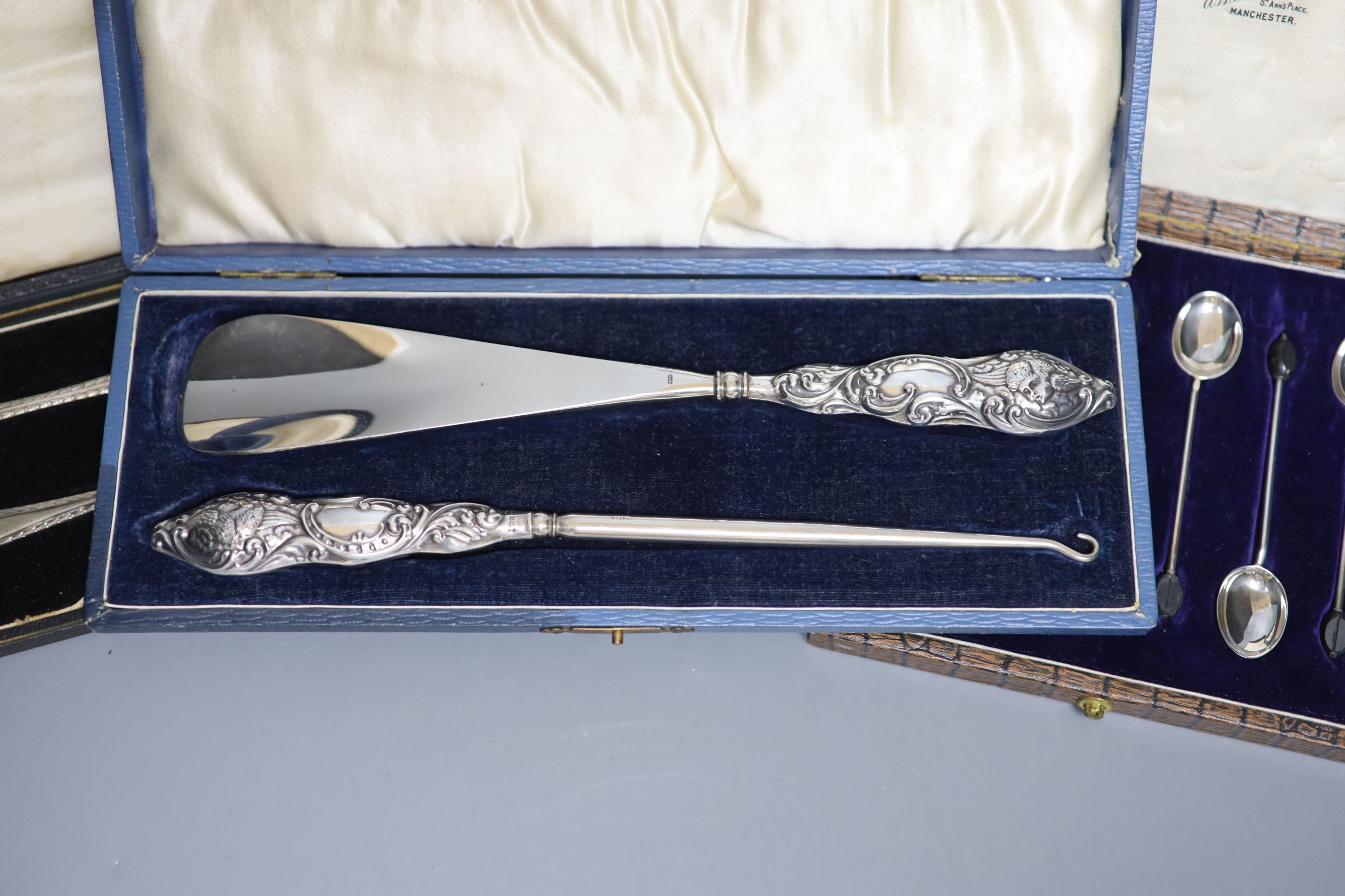 A cased set of six silver bean end coffee spoons, a cased silver spoon and pusher and a cased silver handled shoe horn and button hook.